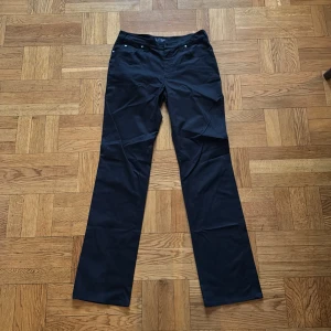 Svarta byxor från Armani Jeans - Snygga svarta byxor från Armani Jeans med en stilren design. Byxorna har en normal passform och är tillverkade i ett mjukt material med stretch för extra komfort. De har en klassisk femficksmodell och ett diskret märke på bakfickan.