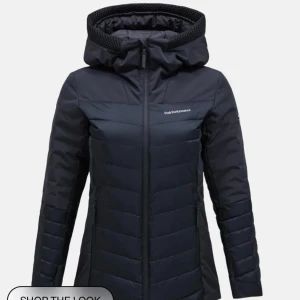 Svart dunjacka från Peak Performance - Snygg svart dunjacka från Peak Performance med dragkedja och huva. Jackan har en stilren design med långa ärmar och är perfekt för kyligare dagar. Den är både funktionell och trendig, vilket gör den till ett måste i garderoben.