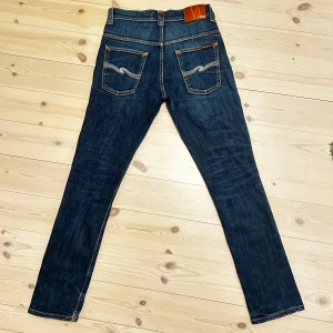 Nudie Jeans  - Otroligt feta mörkblå jeans från Nudie Jeans med vit sömn på bakfickan.  Byxorna är i otroligt bra skick, bara en liten lagning i ena fickan fram som inte märks av. Storlek 30W 32L. Hör av dig ifall det dyker upp någon fråga
