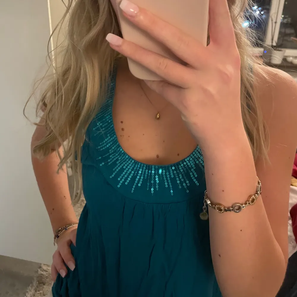 Snygg turkos ärmlös topp från H&M med glittriga detaljer runt halsringningen. Perfekt för att ge en touch av glamour till din outfit. Tillverkad i ett mjukt och bekvämt material.. Yläosat.
