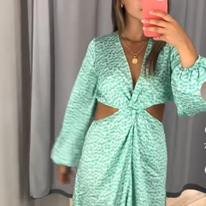 Grön mönstrad klänning - Snygg grön klänning med ett subtilt mönster och en knytning framtill. Klänningen har långa ärmar och en v-ringad design som ger en elegant touch. Perfekt för att sticka ut med stil. Från hm slutsåld super söt 