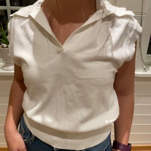 Vit ärmlös topp - Säljer en stilren vit ärmlös topp med krage och v-ringning. Perfekt för en avslappnad och chic look. Passar bra till jeans eller kjol.