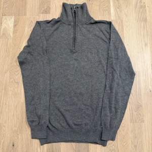 Grå polotröja med dragkedja - Snygg och stilren grå polotröja med dragkedja. Perfekt för kyligare dagar med sin långa ärmar och mjuka material. Tröjan har en ribbad kant vid ärmslut och nederkant för en bekväm passform.