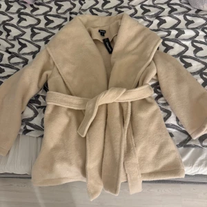 Beige teddyjacka från Boohoo - Mysig beige teddyjacka från Boohoo i storlek Xs/S. Jackan har en skön och varm känsla med ett bälte i midjan för en snygg passform. Perfekt för kyliga höst- och vinterdagar. Den har långa ärmar och en stilren design som passar till allt. Aldrig använt, prislapp är fortfarande på. Fickorna är varma och mjuka. Köpt den för 1000kr men säljer för 600.pris går att diskutera💖