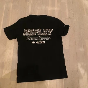 Svart t-shirt från Replay - Säljer en svart t-shirt från Replay med tryck på framsidan. Den är i bra skick och perfekt för vardagsbruk. Storleken är normal och materialet känns mjukt och bekvämt. Passar bra till jeans eller shorts! ( lite slitningar på texten på framsidan).