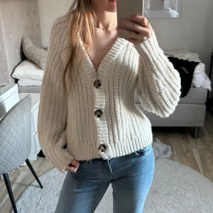 Beige stickad kofta - Kontakta alltid mig innan köp! Säljer en supermysig beige stickad kofta med stora knappar framtill. Den har en v-ringad design och långa ärmar, perfekt för kyliga dagar. Koftan är i bra skick. Perfekt för höst och vinter!