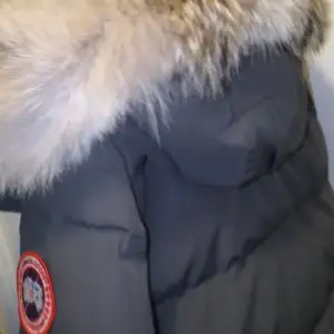 Säljer en svart dunjacka från Canada Goose i mycket bra skick. Jackan har en snygg pälsdetalj runt huvan och stängs med dragkedja och knappar. Perfekt för kalla vinterdagar! 🖤