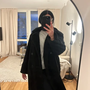 Svart pälsjacka - Säljer en supermysig svart pälsjacka i mycket bra skick. Perfekt för kalla vinterdagar och höstpromenader. Jackan har en oversized passform och långa ärmar, vilket gör den både stilren och bekväm. Den har knappar framtill för enkel stängning. Passar perfekt för både vardag och fest!
