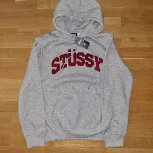 Säljer en snygg grå hoodie från Stussy i storlek XL. Den har en stor röd Stussy-logga på bröstet och är i nytt skick med etikett kvar. Perfekt för höst och vinter! (Skriv innan köp)