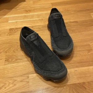Svarta Nike Vapormax i storlek herr 44 - Säljer ett par svarta Nike Vapormax i mycket bra skick. Skorna har en modern design med stickat material och saknar traditionell snörning för en smidig passform. Perfekta för både träning och vardagsbruk. Sulan är i syntet och ger bra dämpning och komfort. Med väldigt bra pris 
