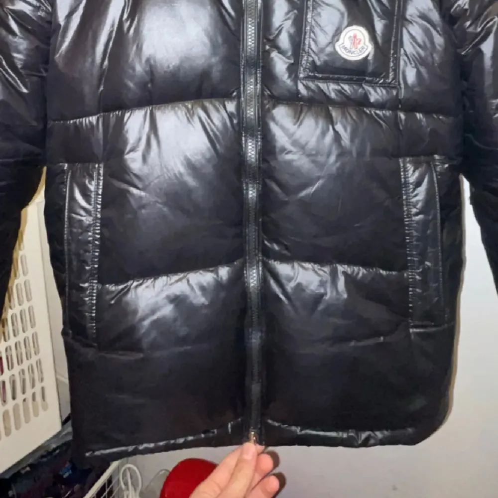 Säljer en snygg svart pufferjacka från Moncler i mycket bra skick. Jackan har en dragkedja med röd och vit detalj, samt en liten logga på bröstet. Perfekt för kalla dagar och håller dig varm och stilren. Passar båda till dag o natt.. Jackor.