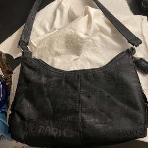 Svart axelväska med textmönster - Säljer en svart axelväska med ett coolt textmönster. Perfekt för vardagsbruk eller en utekväll. Hör av för fler bilder eller frågor 🤍