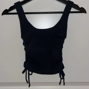 Svart ribbad linnetopp från Zara - Snygg svart ribbad linnetopp från Zara i storlek S. Toppen har en tight passform med fina knytband på sidorna. Perfekt för sommardagar eller en utekväll.