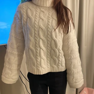 Vit stickad polotröja - Mysig vit stickad polotröja med ett klassiskt flätmönster. Perfekt för kyliga dagar med sin höga krage och långa ärmar. Tröjan har en avslappnad passform och ribbade kanter som ger extra komfort. Passar perfekt till både vardag och mysiga hemmakvällar. Perfket till skidsäsongen också❤️ pris kan diskuteras