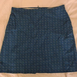 Blå kjol från Noa Noa - Säljer en superfin blå kjol från Noa Noa med små blommiga mönster i gult och blått. Kjolen har en dragkedja baktill och är perfekt för både vardag och fest. Den är i bra skick och passar perfekt till vår och sommar. 🌼