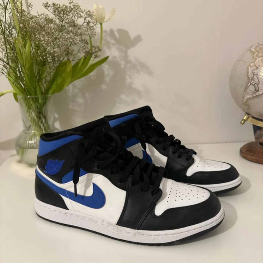 Säljer ett par Nike Air Jordans i svart, vit och blå. Skorna har en klassisk design med snörning och är i mycket bra skick. Storlek; 45,5.. Skor.