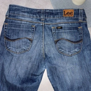 Blå jeans från Lee - Säljer ett par snygga blå jeans från Lee i bra skick. De har en klassisk femficksdesign och är tillverkade i slitstarkt denim. 
