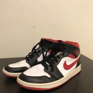 Nike Air Jordan 1s - Säljer ett par klassiska Nike Air Jordans i svart, vitt och rött. Skorna har en snygg design med snörning och den ikoniska Nike-loggan på sidan. Perfekta för både vardag och fest! De är i mycket bra skick och redo för nya äventyr. Nypris 2399kr✅