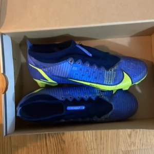 Blå och gula fotbollsskor från Nike - Säljer ett par snygga blå och gula Nike fotbollsskor i nytt skick. De har en modern design med en tight passform och är perfekta för fotbollsträning eller match. Skorna har en slitstark sula och är gjorda för att ge bra grepp på planen. Kommer i originalkartong Tveka ej på fråga om bilder jag kan gå ner i pris vid intresse dm till mig är alltid aktiv 🙌⚽️