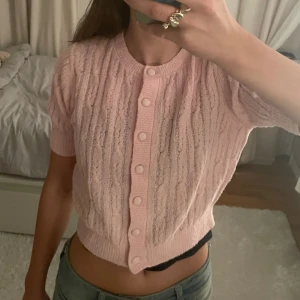 Rosa kofta från & Other Stories - Säljer en superfin rosa kofta från & Other Stories. Den är stickad med ett snyggt kabelmönster och har korta. Koftan har knappar hela vägen som går att knäppa upp och är i mycket bra skick. Passar perfekt till både jeans och kjol. 🌸