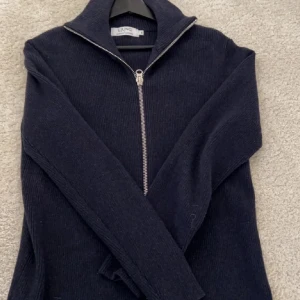 Mörkblå helzip/fullzip tröja - Säljer en stilren mörkblå ribbad tröja från Ljung by Marcus Larsson i storlek S. Tröjan har en dragkedja framtill och är perfekt för både höst och vinter. Den är långärmad och gjord i ett mjukt material som håller dig varm. Passar både till vardags och lite finare tillfällen. Nypris 1400 kronor.