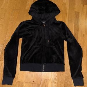 Svart Juicy Couture tröja - Säljer en svart Juicy Couture i storlek XS. Den har en dragkedja framtill och en mysig huva, den är i bästa skick och använd någon gång bara