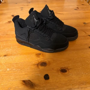 Nike Air Jordan 4 Black Cats - Säljer ett par svarta Nike Air Jordan 4 Black Cats i mycket bra skick. De är helt svarta med snygg snörning och den klassiska Jumpman-loggan på tungan och hälen. Perfekta för både vardag och fest! 🖤