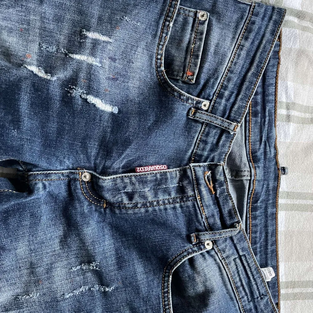 Säljer ett par snygga blå jeans från Dsquared2 i storlek 30. De har en cool distressed look med slitningar och en klassisk femficksdesign. Perfekta för en avslappnad stil med en touch av edge. Passar både till vardags och fest!. Jeans & Byxor.