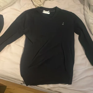 Svart kashmirtröja från Peak Performance - Säljer en stilren svart kashmirtröja från Peak Performance i storlek S. Tröjan har en v-ringad design och ett diskret broderat emblem på bröstet. Perfekt för både vardag och lite finare tillfällen. Supermjuk och bekväm!