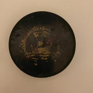 Svart ishockeypuck med guldfärgad logotyp -  Jag säljer en bok som Västra Frölunda har använt🏒