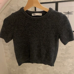 Grå stickad tröja från Zara - Säljer en superfin grå stickad tröja från Zara. Den är kortärmad och har en ribbad kant vid halsen och ärmsluten. Perfekt för höst och vår när det är lite kyligt men ändå inte för kallt. Tröjan är i storlek XS och är i nyskick💓 Hör av dig vid frågor eller intresse 💓