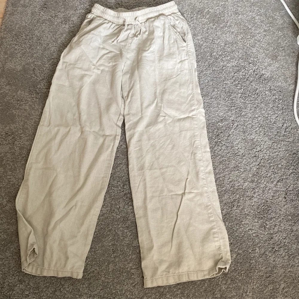 Säljer ett par bekväma och luftiga beige linnebyxor. De har en elastisk midja och en avslappnad passform som är perfekt för varma dagar. Byxorna är i ett mjukt och skönt material som andas bra.. Jeans & Byxor.