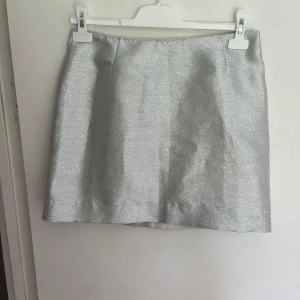 Glitter kjol - Jättefin glittrig kjol i en silverfärg. Sitter högmidjat och slutar perfekt under rumpan. 