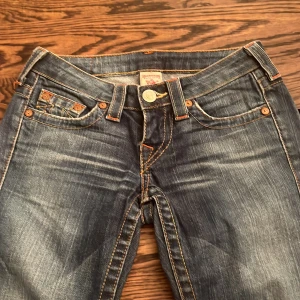 Skinny bootcut från True Religion - Jättesnygga detaljerade low-rise blå jeans från True Religion  💕dessa jeansen är vintage och finns inte att köpa längre ❣️(i bilderna ser jeansen gråa ut men de är egentligen blåa) 