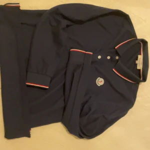 Mörkblå pikétröja från Moncler - Snygg mörkblå pikétröja från Moncler! Helt nyskick, fick in tröjan från ett företag och nu ska jag sälja den. Köpt för 750 kr. Säljer för 500 kr. Mer frågor och bilder får ni i dm. Kan sänka vid snabb affär.