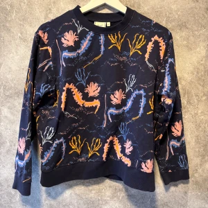 Mönstrad tröja från Emma och Marlena - Snygg tröja från Emma och Marlena med ett färgglatt mönster i blått, rosa och orange. Tröjan har en rund hals och långa ärmar, perfekt för att liva upp garderoben. Passar bra till både jeans och kjol.