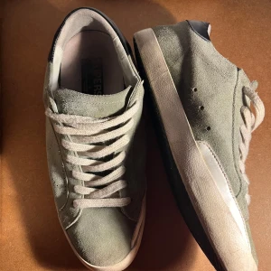 Gröna sneakers från Golden Goose - Snygga gröna sneakers från Golden Goose med vit sula och snörning. Skorna har en svart detalj vid hälen och är tillverkade i mocka. Perfekta för en avslappnad stil.  
