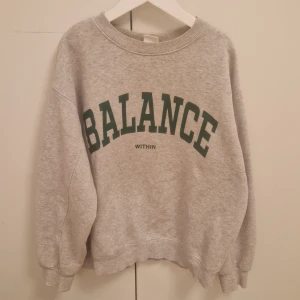 Grå sweatshirt med text - Säljer en grå sweatshirt med texten 'BALANCE' i grönt på framsidan. Tröjan har en rund halsringning och långa ärmar. Perfekt för en avslappnad stil. Fint skick!