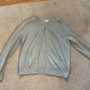 Ljus blå kofta från H&M - Säljer en stilren ljus blå kofta från H&M Basic-kollektionen. Koftan har långa ärmar och knappar framtill. Perfekt för lager-på-lager och passar till många olika outfits.