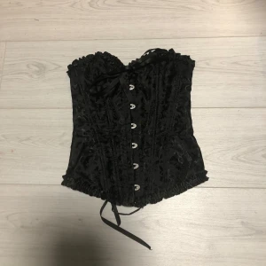 Svart korsett med snörning - Svart korsett med dekorativt mönster och snörning på baksidan. Älskar den men den kommer tyvärr aldrig till användning. Köpt på Plick för något år sen 🫶🫶