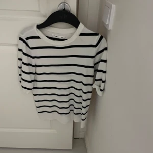 Randig tröja från Gina Tricot - Säljer en stilren vit och svart randig tröja  Tröjan har korta ärmar och en rund halsringning. Perfekt för en avslappnad look. 🖤🤍