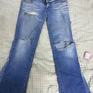 Blå slitna jeans - Säljer ett par blå jeans med slitningar och hål för en cool look. De har en klassisk femficksdesign och en ljus tvätt. Perfekta för en avslappnad stil. Dessa kommer inte till någon annaväning därför säljer jag.