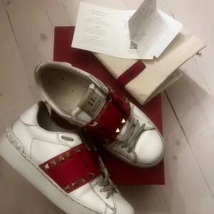 Valentino sneakers med nitar - Såå snygga röda Valentino Garavani sneakers med guldiga spikar😍Sjukt ovanliga och gör en hel outfit! Dem är i bra men använt skick (bild 4,5 visar nåra fläckar skorna har), men inget man tänker på vid användning. Box, kvitto och dustbag medföljer!