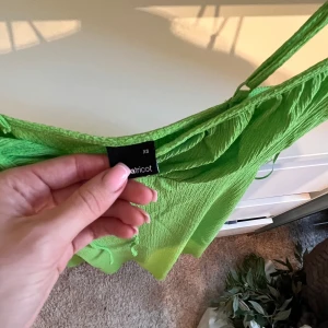 Grön klänning från Bik Bok - Snygg grön klänning från Bik Bok i storlek XS. Klänningen har smala axelband och en knytning framtill som ger en fin detalj. Perfekt för sommarens varma dagar! 💚