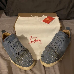 Blå sneakers från Christian Louboutin - Snygga blå sneakers från Christian Louboutin med nitar på tån. Skorna har snörning och en klassisk design med en modern twist. Perfekta för att ge din outfit en edgy look. Storlek 43-44, hör av dig vid funderingar 🤩 byten är av intresse 