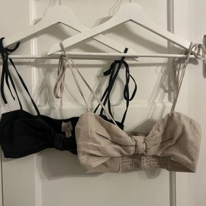 Mörkgrå/svart och beige linnetopp  - Två snygga linnetoppar från H&M i mörkgrå/svart och beige. De har knytband vid axlarna och en söt rosett framtill. Perfekta för varma dagar med sin lätta och luftiga design. Kan även köpas styckevis för 80kr styck. Aldrig använda!!!!