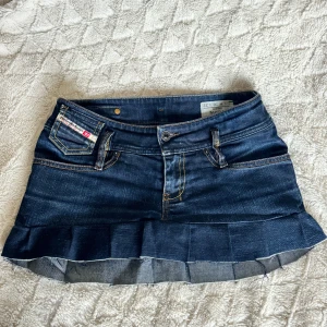 Jeanskjol med volangdetalj - Trendig jeanskjol från Diesel med volangdetalj i nederkant. Kjolen har en klassisk femficksdesign och en mörkblå tvätt. Perfekt för en snygg outfit. Omsydd från jeans (noggrant)! 