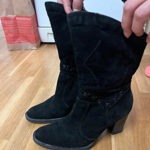 Svarta mockastövletter med klack - Säljer ett par snygga svarta stövletter i mockaimitation. De har en bekväm klack och spetsig tå, vilket ger dem en elegant look. Perfekta för höst och vinter, och de passar både till vardags och fest. Använda men i bra skick!