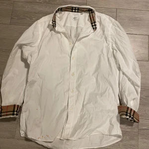 Burberry skjorta  - Nästan ny burberry skjorta. Använd några få gånger men tyvärr mycket fläckig vid nedre delen av skjortan… storlek M-L (KOLLA BILDERNA)