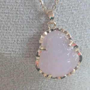 Rosa Buddha-halsband med guldkant - Ett vackert halsband med en rosa Buddha-berlock inramad i guld. Kedjan är tunn och elegant,Berlocken har en fin glans och detaljerad design.i rostfritt stål.ny